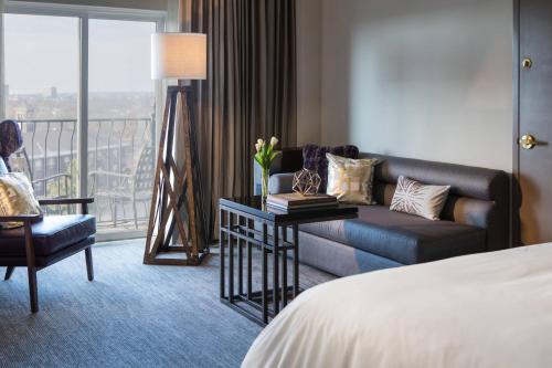 オクラホマシティにあるRenaissance Waterford Oklahoma City Hotelのベッド、ソファ、窓が備わるホテルルームです。