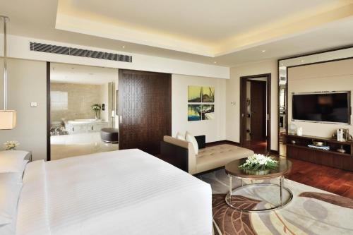 a bedroom with a bed and a living room at Kochi Marriott Hotel in Cochin