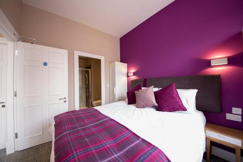 um quarto roxo com uma cama com paredes roxas em The Spires Serviced Apartments Edinburgh em Edimburgo