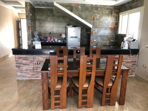 una cucina con tavolo in legno, sedie e frigorifero di Senior chalet in Haciendabay for rent a El Alamein