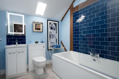 La salle de bains est pourvue d'une baignoire, de toilettes et de carrelage bleu. dans l'établissement Walltown Farm Cottage, à Brampton