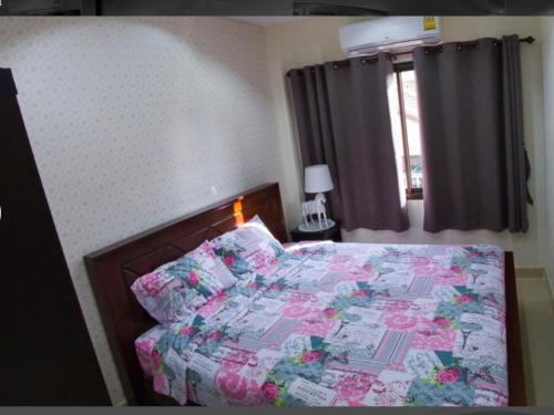 a bedroom with a bed with a floral quilt and a window at Junior Apartment in Pattaya