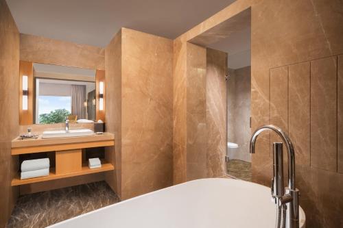 a bathroom with a tub and a sink and a mirror at Courtyard by Marriott Tiruchirappalli in Tiruchirappalli