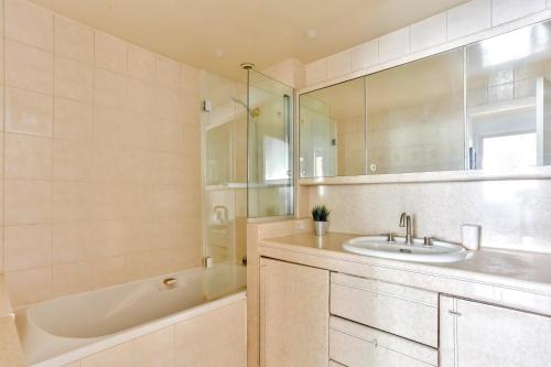 a bathroom with a sink and a bath tub and a mirror at Appartement Quartier Arc de Triomphe Free Netflix in Paris