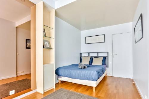 a bedroom with a blue bed in a white room at Appartement Quartier Arc de Triomphe in Paris