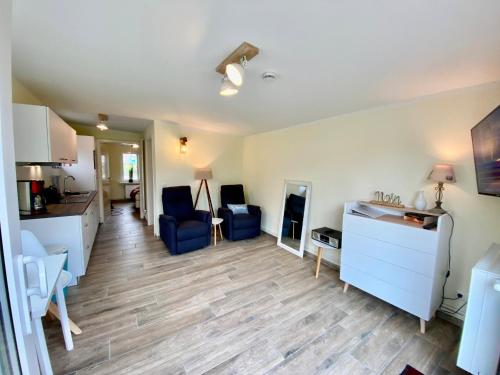 sala de estar con sillas azules y cocina en Am Oland 11 Bungalow, en Büsum