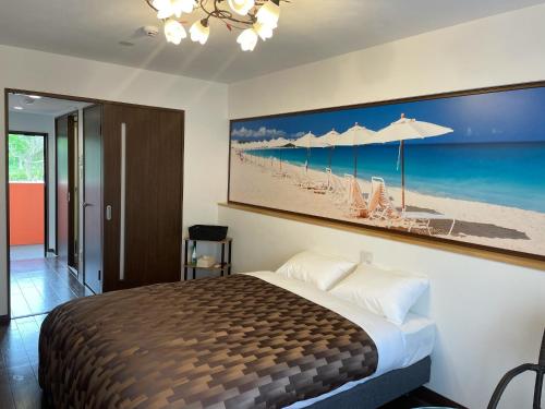 ein Schlafzimmer mit einem Bett mit einem Bild vom Strand in der Unterkunft Ao-Ao-Hotel - Vacation STAY 32070v in Nago