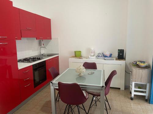 cocina con armarios rojos, mesa y sillas en Appartamento al centro di Scario, en Scario