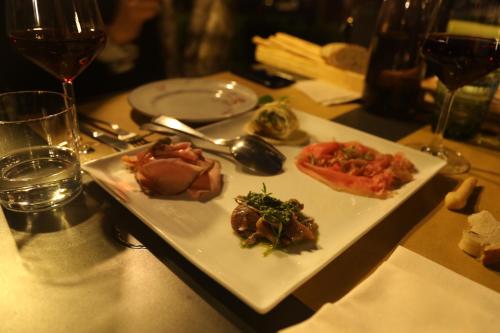um prato de comida numa mesa com copos de vinho em Agriturismo em Tigliole