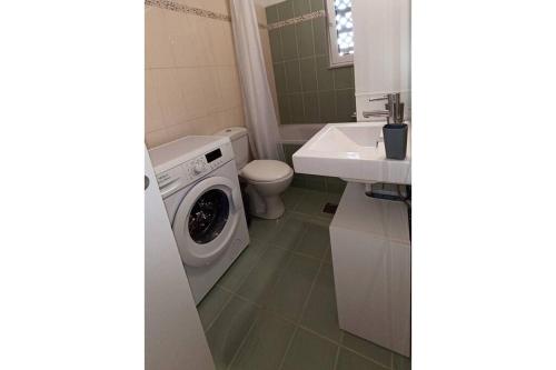 uma casa de banho com uma máquina de lavar roupa e um lavatório em Bougainvillea apartment em Zakynthos