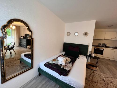 a bedroom with a bed with a mirror and a kitchen at Charmantes Apartment in Offenburg
