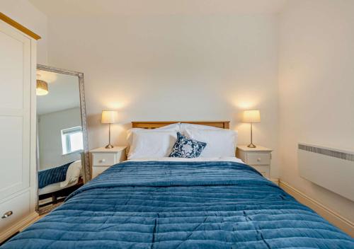 a bedroom with a blue bed and a mirror at Bayview Apartment - Machynys in Llanelli