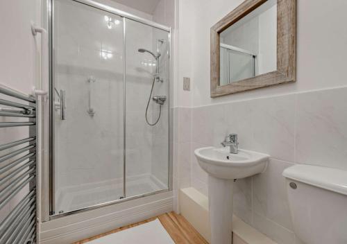a white bathroom with a shower and a sink at Bayview Apartment - Machynys in Llanelli