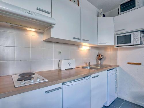 une cuisine avec des armoires blanches, un évier et une cuisinière dans l'établissement Studio confortable, idéal pour 4 pers, situé au pied des pistes à Gourette - FR-1-400-62, à Gourette