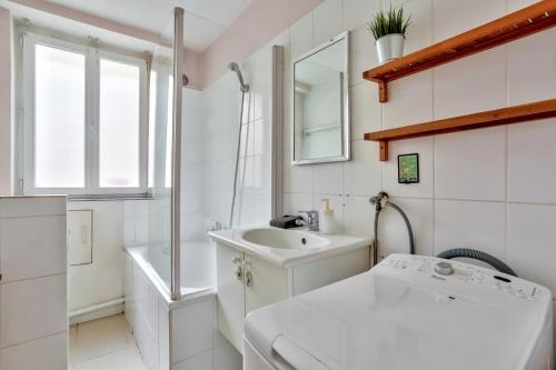 une salle de bain blanche avec un lavabo et un miroir dans l'établissement Appartement Quartier Pigalle Free Netflix, à Paris