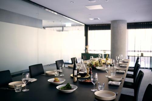 a dining room with a long table with wine glasses at Midnight Hotel, Autograph Collection in Canberra