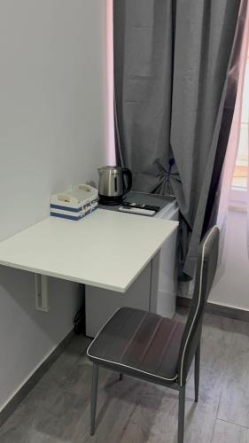 a white table with a chair and a pot on it at Anyma Home in Crotone