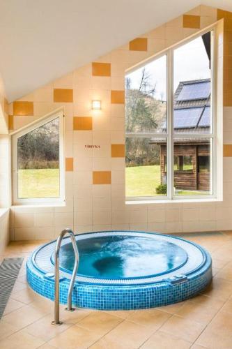 a hot tub in a room with two windows at Hotel Sipox in Štrba