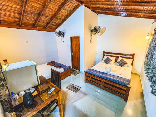 a bedroom with two beds and a table and a mirror at Birds Paradise Inn in Udawalawe