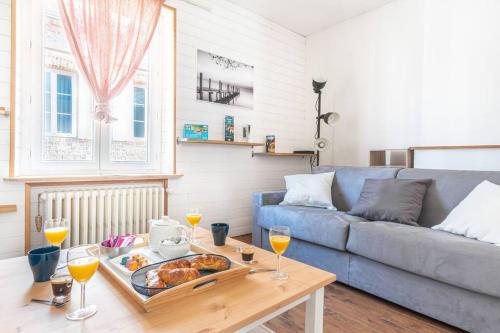 een woonkamer met een bank en een tafel met een dienblad met eten bij La Maison de Jade - Etretat Centre - 6 pers in Étretat