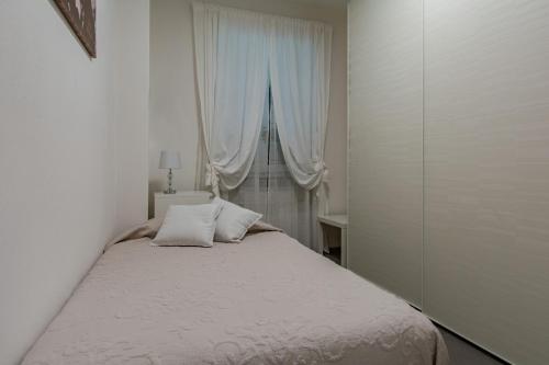 a bedroom with a bed with white sheets and a window at La passione al mare in Marina di Massa
