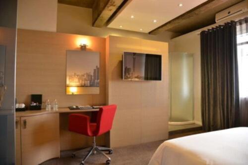 a hotel room with a desk and a red chair at Reef Hotel in Johannesburg