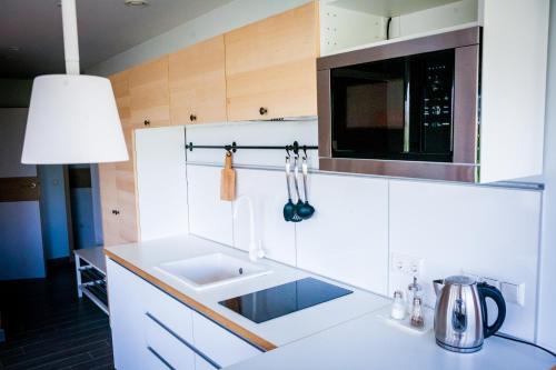 a white kitchen with a sink and a microwave at Vila Nikolas in Druskininkai