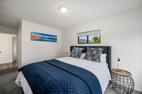 a bedroom with a bed with a blue comforter and two windows at Teemos Retreat - Family and Friends, lots of space, big backyard in Rotorua