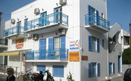 ナクソス・コラにあるVery-Kokkos Pension 2の青いバルコニー付きの白い建物で、正面にオートバイが駐車しています。