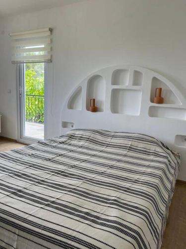 a white bedroom with a bed with a striped blanket at Doğa içinde havuzlu villa in Aydın