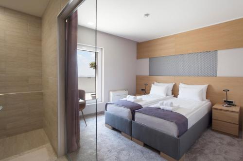 a bedroom with two beds and a walk in shower at Prince Rooftop in Belgrade