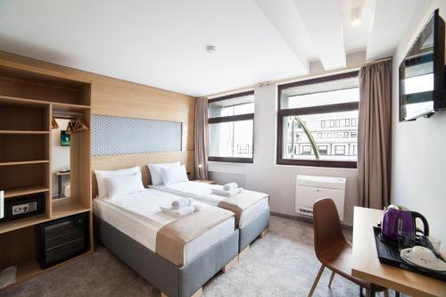 a hotel room with two beds and a desk and a television at Prince Rooftop in Belgrade