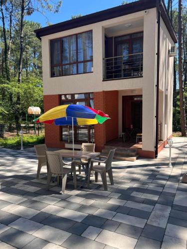 uma mesa com cadeiras e um guarda-sol em frente a uma casa em Villa Premium Shekvetili em Shekhvetili