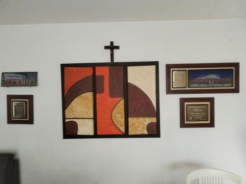 a cross hanging on a wall with framed pictures at Casa CODHE - Sebastián Galicia Carrera in Córdoba