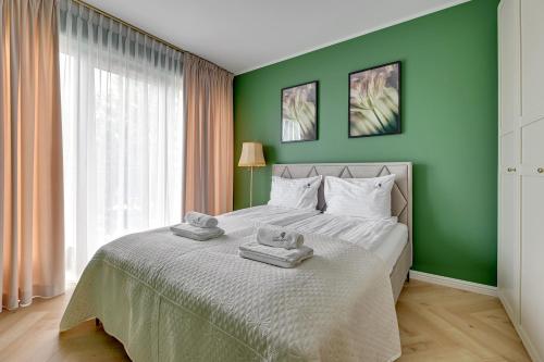 a green bedroom with a bed with towels on it at Willa Dattero Gdynia by Lion Apartments in Gdynia