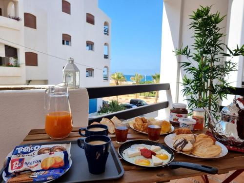 a table with breakfast food on a balcony at Prestige Apartment Oued Laou in Oued Laou