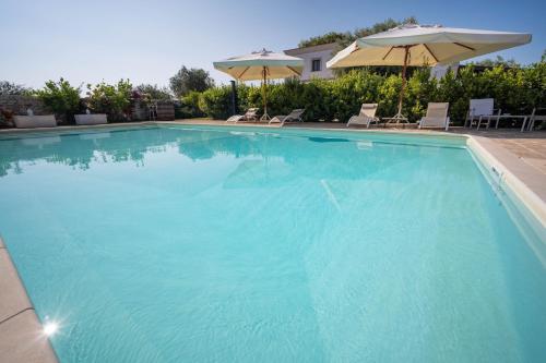 a large blue swimming pool with chairs and umbrellas at TERRA TERRA - Masseria Minunni in Conversano