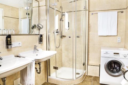 a bathroom with a shower sink and a washing machine at Hotel Suitess in Dresden