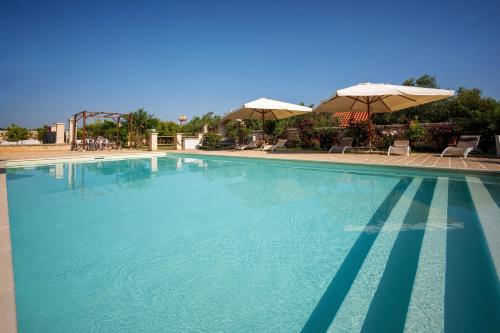 a large swimming pool with two umbrellas and chairs at TERRA TERRA - Masseria Minunni in Conversano