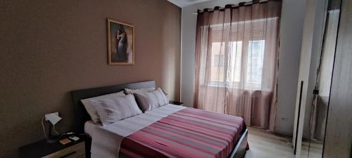 1 dormitorio con 1 cama con manta a rayas y ventana en INTERNO NOVE - appartamento a Corsico en Corsico