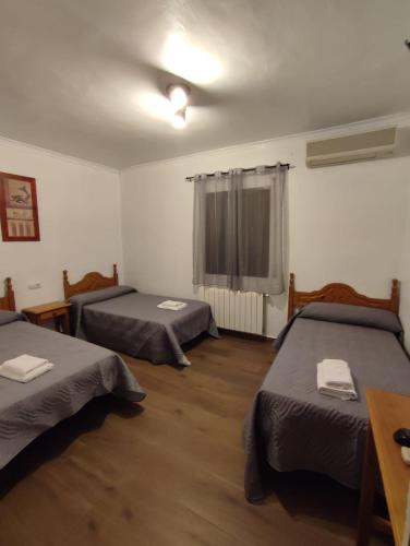 a room with three beds and a table and a window at El Cruce Hornos in Hornos