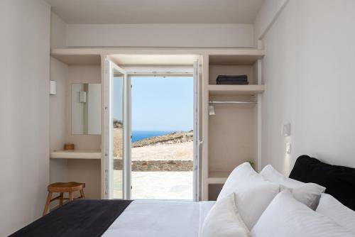 a bedroom with a bed and a view of the ocean at Kythea Suites Kythnos in Kithnos