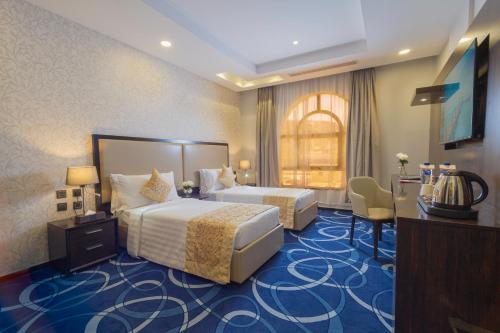 a hotel room with two beds and a desk at Cloud City Hotel in Al Baha