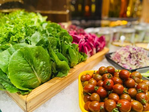 胡志明市百利宫西贡酒店的桌子上摆放着自助餐台，上面放着生菜和西红柿。