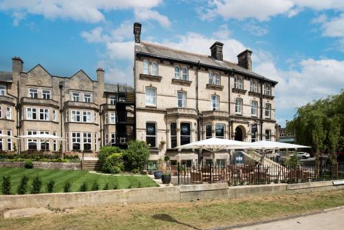 哈羅蓋特的住宿－The Harrogate Inn - The Inn Collection Group，一座大型石头建筑,前面有遮阳伞
