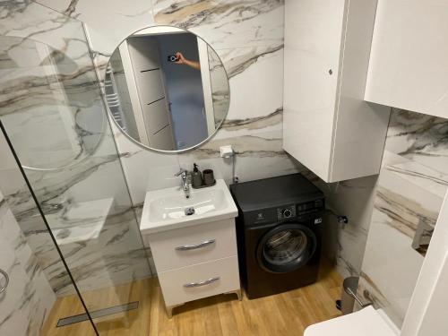 a bathroom with a sink washing machine and a mirror at Apartament Centrum Łeba in Łeba