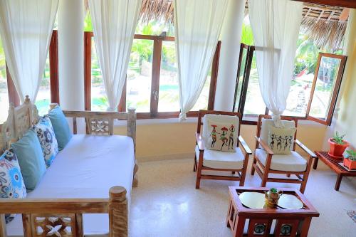 a living room with a bed and two chairs at Tembo Baharini Beach Cottage in Malindi