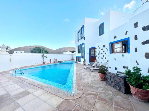 a villa with a swimming pool and a building at Doble clásica con desayuno, Wifi y hermosa piscina en Yaiza in Yaiza