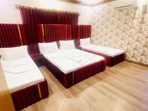 drie bedden in een kamer met rode scheidingswanden bij Rehaish Inn Model Colony in Karachi