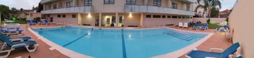 a large swimming pool in front of a building at Hotel La Fontaine in Esmoriz